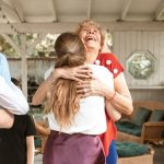 A heartwarming reunion with family members hugging and smiling in a cozy indoor setting.