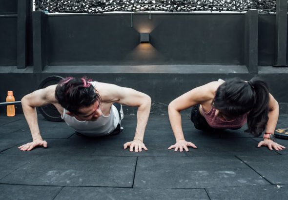Two adults doing push-ups in an indoor gym setting in Mexico City, promoting a fit and healthy lifestyle.